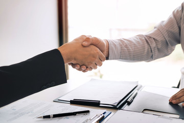 Manager and employee interview concept with handshake after talking about contract signing.