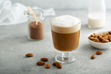 Almond milk latte with thick foam in a glass