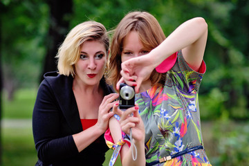 young girls take pictures of each other in the park