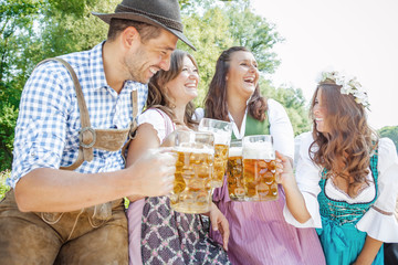 Five friends, men and women, having fun on Bavarian RIver and clinking glasses with beer