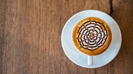 Hot coffee, a cup of cappuccino with latte art on wooden background. White ceramic cups top view closeup, place for text