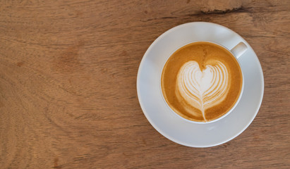 Hot coffee, a cup of cappuccino with latte art on wooden background. White ceramic cups top view closeup, place for text