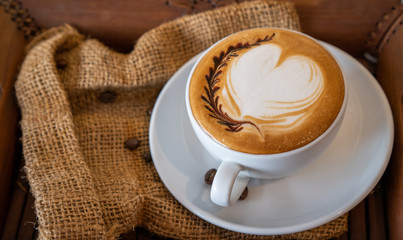Hot coffee, a cup of cappuccino with latte art heart on wooden background. White ceramic cups.Love coffee.
