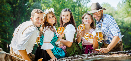 Freunde in bayerischen Tracht feiern an der Isar und trinken Bier. Oktoberfest München