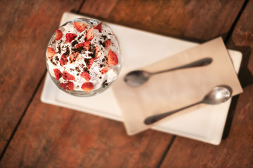 Top view ice cream with strawberries and cocoa powder topping decorated on top and wooden table background in the coffee shop