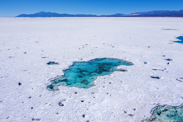Drone point of view of an emerald lake in the desert of Salinas Grandes, one of the most spectacular landscape on earth. Long extension of white snowy salt in the desert in Jujuy province, northern Ar