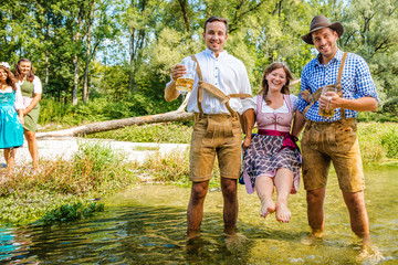 friends having fun on Bavarian RIver(isar) Two men carry woman over the river