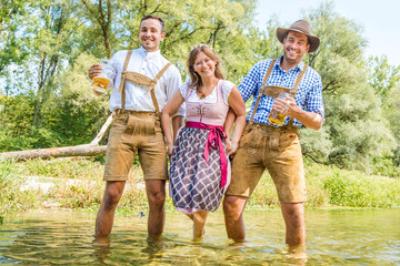 friends having fun on Bavarian RIver(isar) Two men carry woman over the river