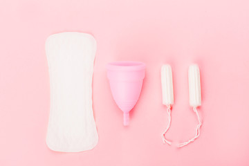 Various sanitary products on pastel pink background.