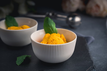 Mango ice cream sorbet with mint leaves on dark background