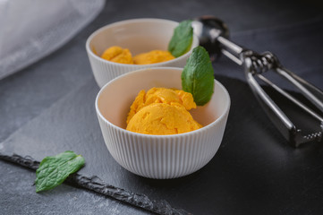 Mango ice cream sorbet with mint leaves on dark background