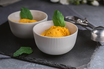 Mango ice cream sorbet with mint leaves on dark background