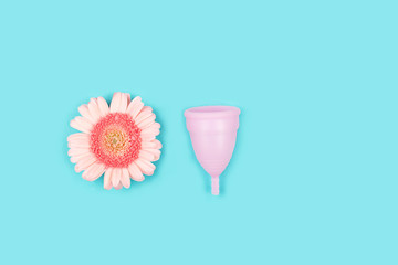 Pink menstrual cup and a flower on blue background.