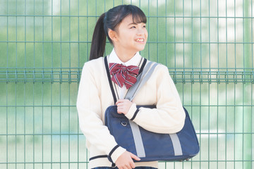 フェンスの前を立つ女子校生