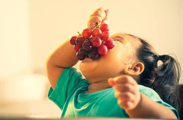 Foto op Plexiglas kid eating grape funny vintage style © singkham