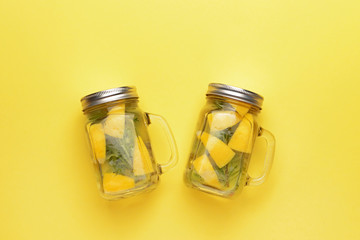 Mason jars of infused water on color background