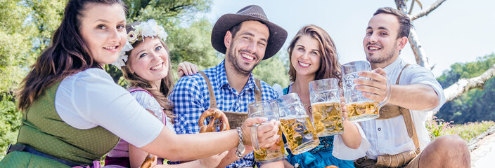 Friends in Bavarian costume celebrate on the river Isar and drink beer. Oktoberfest munich