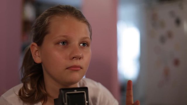 teen girl looks into the mine of a medium format camera aimed at us, taking picture of you.