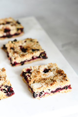 Honeysuckle crumble cake sliced into pieces on grey marble tray. Homemade streusel berries pie.  Selective focus. Haze effect