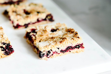 Honeysuckle crumble cake sliced into pieces on grey marble tray. Homemade streusel berries pie.  Selective focus