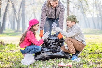 Young volunteers picking up trash in the park. Volunteer and ecology concept
