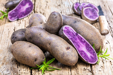 close-up view of fresh raw purple potatoes on wooden table 