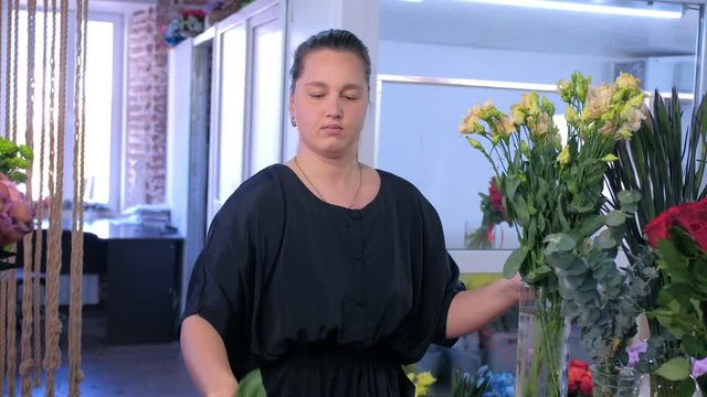 Floral business concept. Florist woman works makes bouquet beige eustoma alstroemeria in flower shop for sale. She puts flowers from vase creates professional bunch in floristic studio store.