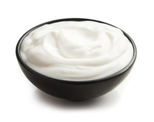 Sour cream or yoghurt in black bowl isolated on white background