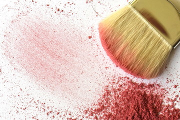 Powdered pink shiny shimmer, or blush loose on the white textured background with blurred makeup brush in the corner. Visible brush stroke, smear. Top view, flatlay, copy space. Beauty routine concept