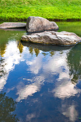 Fototapeta na wymiar large stones in the river with the reflection of trees