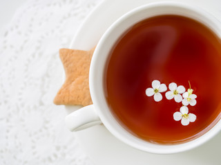 White flowers flowing in a white cup of tea