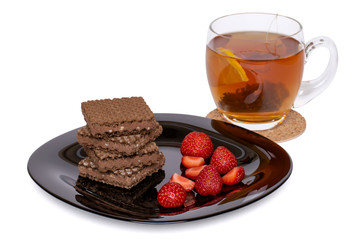 Сrunchy chocolate sandwich wafers with cocoa cream and nuts filling, whole berries and pieces of strawberries, black tea with lemon in a glass mug. 