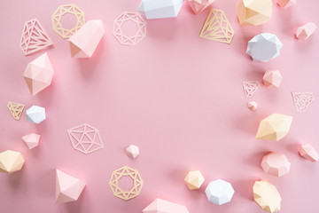 A variety of faceted gemstones, made of paper on a pink background.