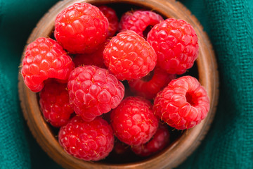 Raspberries in a Bowl, View From Above. Fresh Ripe Raspberries in a Wooden Bowl on Green Background Close Up Top View