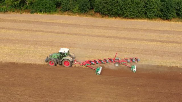 Aerial view of a agricultural tractor with a red plow during field work on one agricultural field in germany