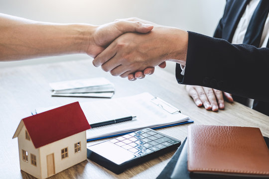 Finishing to successful deal of real estate, Broker and client shaking hands after signing contract approved application form, concerning mortgage loan offer for and house insurance