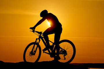 Obraz premium Silhouette Young man of cycling on sunset background. Bicycle and ecology lifestyle concept.