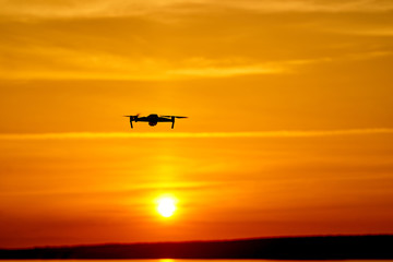 Naklejka na ściany i meble drone quadcopter with digital camera flying at sunset