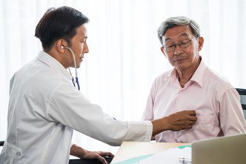 Doctor listening to patient's heart rate with stethoscope in medical office.
