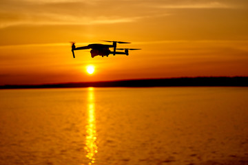 Fototapeta na wymiar drone quadcopter with digital camera flying at sunset. Beautiful sunset on the river