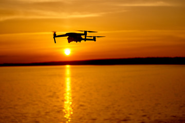 drone quadcopter with digital camera flying at sunset. Beautiful sunset on the river