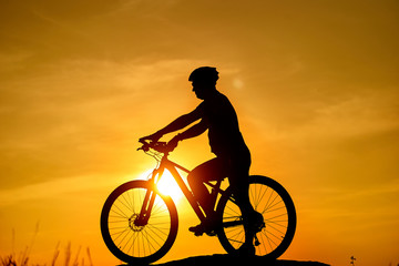 Fototapeta na wymiar Silhouette of the cyclist riding on a sports bike at sunset. Active Lifestyle Concept.