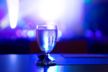 1 glass of water placed on the table In the night restaurant with colorful light.