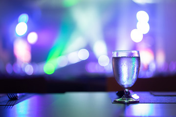 1 glass of water placed on the table In the night restaurant with colorful light.
