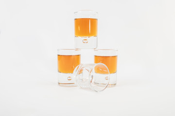 Three small glasses filled with luxurious whiskey next to an empty glass, isolated on a white background