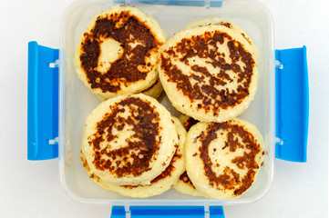 cheesecakes to plastic container, top view on white background