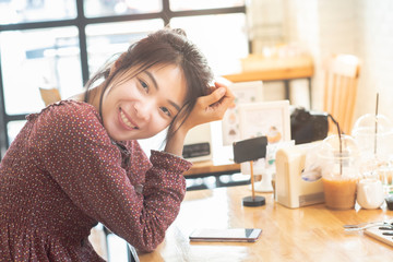 Happy asian woman teenager in casual dress face look at camera with big smile sit on table in coffee shop with smart mobile phone on table,lifestyle teenager in new generation with copy space.