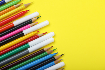 Multicolored markers and pencils at bright background