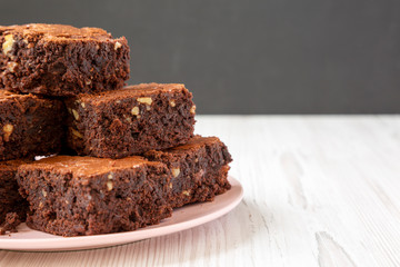 Homemade chocolate brownies on a pink plate, side view. Space for text.