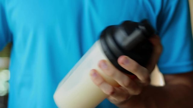 Close-up of an athlete shaking a protein shake to mix it.